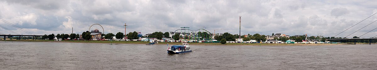 Zicht op de "Größte Kirmes am Rhein" vanaf de andere Rijnoever, op de voorgrond de veerboot naar de kermis