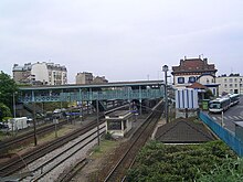 Übersicht über Bahnhof, Gleise, Bahnsteige, Fußgängerbrücke und Passagiergebäude