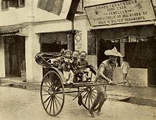 Old photo of four children in a rickshaw pulled by a man