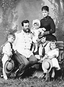 Cliché noir et blanc. Père assis : uniforme. Mère debout : longue robe sombre. 3 fils en marins. Petite fille : layette.