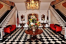 The foyer has checkered marble flooring and dual staircases. WVGovernorsMansionFoyer.jpg