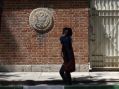 Giovane donna passeggia davanti alla facciata della vecchia ambasciata degli Stati Uniti (tana dello spionaggio degli Stati Uniti) - Teheran - Iran (7383372934).jpg