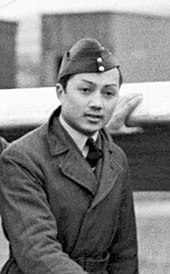 Photo d'un homme d'origine asiatique en tenue militaire, portant une casquette et vêtu d'un caban.