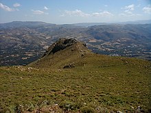 Atsipades Korakias seen from southwest.The sanctuary is on the more distant part of the outcrop. The Ayios Vasilios Plain is visible in the background. Atsipades peak.jpg