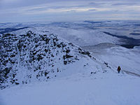 A walker gaun doon the tourist peth, seen frae the summit in Januar 2010.