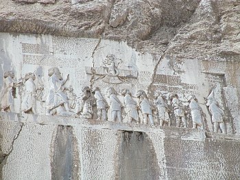 Die Behistun-Inschrift samt Relief; sie zeigt Dareios I., der über die acht „Lügenkönige“ richtet, die sich gegen erhoben haben