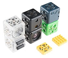 A set of Cubelets, including a temperature and light sensing cubes (black), and speaker and drive cubes (transparent) Cubelets Six Kit (15311725944).jpg