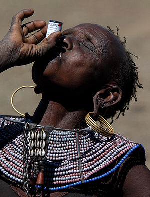 a Pokot woman swallows a dose of deworming medication
