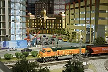 A freight train travels through a busy city in the Modern Era section of EnterTRAINment Junction. Entertrainment Junction Modern Era.jpg