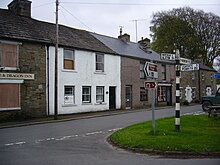 View of row of houses including the Post Office. The boarded-up pub 'The George and Dragon' on the left. Garrigill in May 2014.JPG