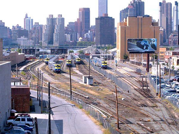 Looking west at the station (to the right of the fence) and yard (to the left); the brick building to the right is ventilation for the Queens–Midtown 