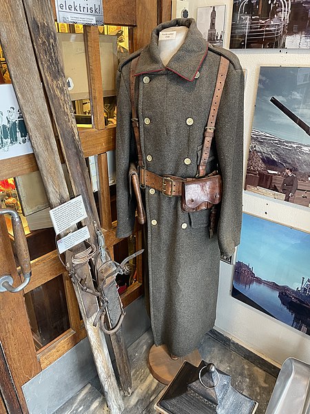 File:Lofoten Krigsminnemuseum WW2 Museum Norway Exhibits by entrance Norwegian army uniform greatcoat belt 1940 Hæren frakk belte tasker reimer rød passepoil sivile knapper German skis used by Org Todt mended binding Tyske ski Photos IMG.jpg