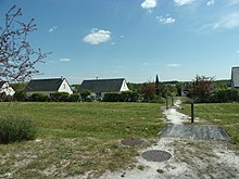 Photographie en couleurs de pavillons modernes séparés par de grands espaces non construits.