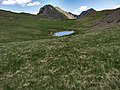 Monte Tombea, la conca pascoliva della Piana degli Stor, la pozza d'abbeverata e a sinistra Cima Tombea mentre a destra il Dosso delle Saette