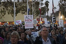 A protester holds up a sign that reads "Act Now - Protect Mueller".
