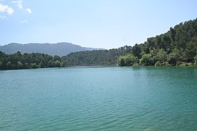 Cliché digitale a colori.  Uno specchio d'acqua circondato da alberi, lontano dalle montagne.