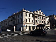 Il fabbricato viaggiatori visto dall'ingresso della vicina autostazione ARST; dal cancello alla sinistra dell'edificio usciva in origine il raccordo ferroviario per il porto