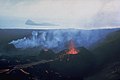 English: Lava flows issue from three small cinder cones on the newly formed island of Surtsey on August 27, 1966. Surtsey began erupting in November 1963 and soon formed a new island. Lava effusion began in April 1964, ensuring that the new island remained permanent. Eruptions at Iceland's newest island continued until 1967. The small island of Jolnir in the background began growing 0.8 km SW of Surtsey at the end of October 1965. It repeatedly was destroyed and grew again above the sea surface before it ceased activity on August 10, 1966.Photo by Richie Williams, 1966 (U.S. Geological Survey).