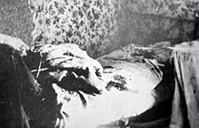 Unmade and messy bed; a pistol is visible on the bed