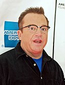 Kopfschuss eines erstaunten Mannes mit Brille, der ein schwarzes, aufgeknöpftes Hemd trägt.