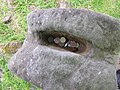 Coins left as mementos in a receptacle between the Janus figure's heads