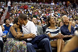 US President Barack Obama and his wife Michelle Obama kissing for the kiss cam while Malia Obama and Joe Biden watch on the jumbotron during a basketball game in Washington, DC Barack and Michelle Obama kissing at a basketball game.jpg