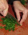 „Hacken“ von Petersilie mit einem Kochmesser („Wiegefunktion“ des Messers)