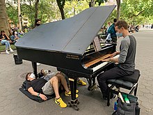 Colin Huggins playing a grand piano in Washington Square Park, New York City Colin Huggins playing piano with listeners.jpg