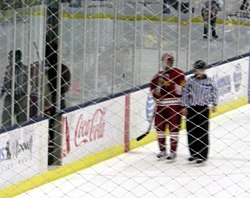 A player from the Ferris State Bulldogs men's ice hockey team being escorted to the penalty box. Ferris State penalty.JPG