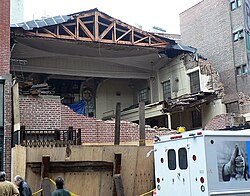 Demolition of the Rivington Street building of the First Roumanian-American Congregation, formerly the First German Presbyterian Church (c.1857). The building was surrounded on the first floor by plywood hoarding. The second and third floors are partially open to the street, and the interior can be seen. Part of the roof has also been torn away, and the joists and trusses are exposed. First Roumanian-American destroyed.jpg