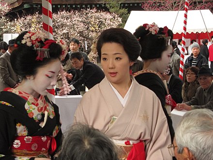 Mature geisha (center) ordinarily wear subdued clothing, makeup, and hair, contrasting with the more colourful clothing, heavy makeup, and elaborate hair of maiko (apprentices; left and right).