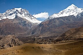 Vista da zona de Muktinath (ao fundo); a aldeia mais próxima é Jharkot; o vale entre as montanhas do fundo conduz à portela de Thorong La