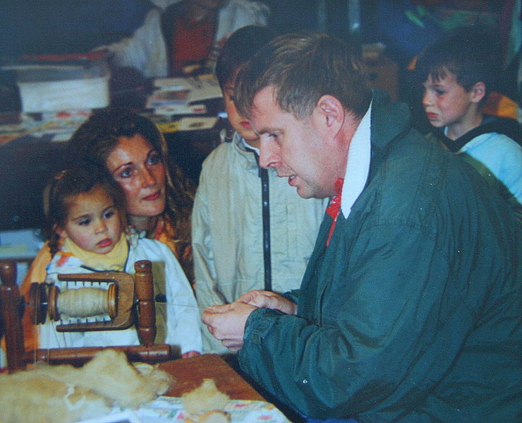 File:Man demonstrates the operation of the spinning wheel to a woman and her little daughter.jpg