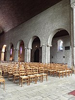 Photographie d'une nef d'église avec des arcades retombant sur des piliers.