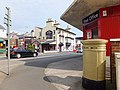 The west side of the box showing the stamp dispenser, plus the entrance to the post office and the Manx Arms pub diagonally across Main Road.