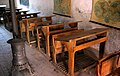 Detalle de bancos, estufa de leña y mapas en la antigua «Escuela Nacional» de Sesga, Ademuz (Valencia).