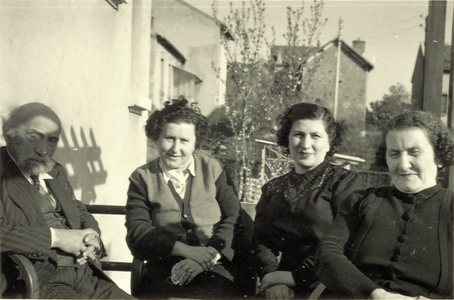 Photographie en noir et blanc d'un homme et de trois femmes assis sur une terrasse.