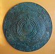 An Ancient Greek warrior's shield--its circular shape and gently sloping surface, with a central raised area, is a shape shared by many shield volcanoes. Bronze votive shield.JPG