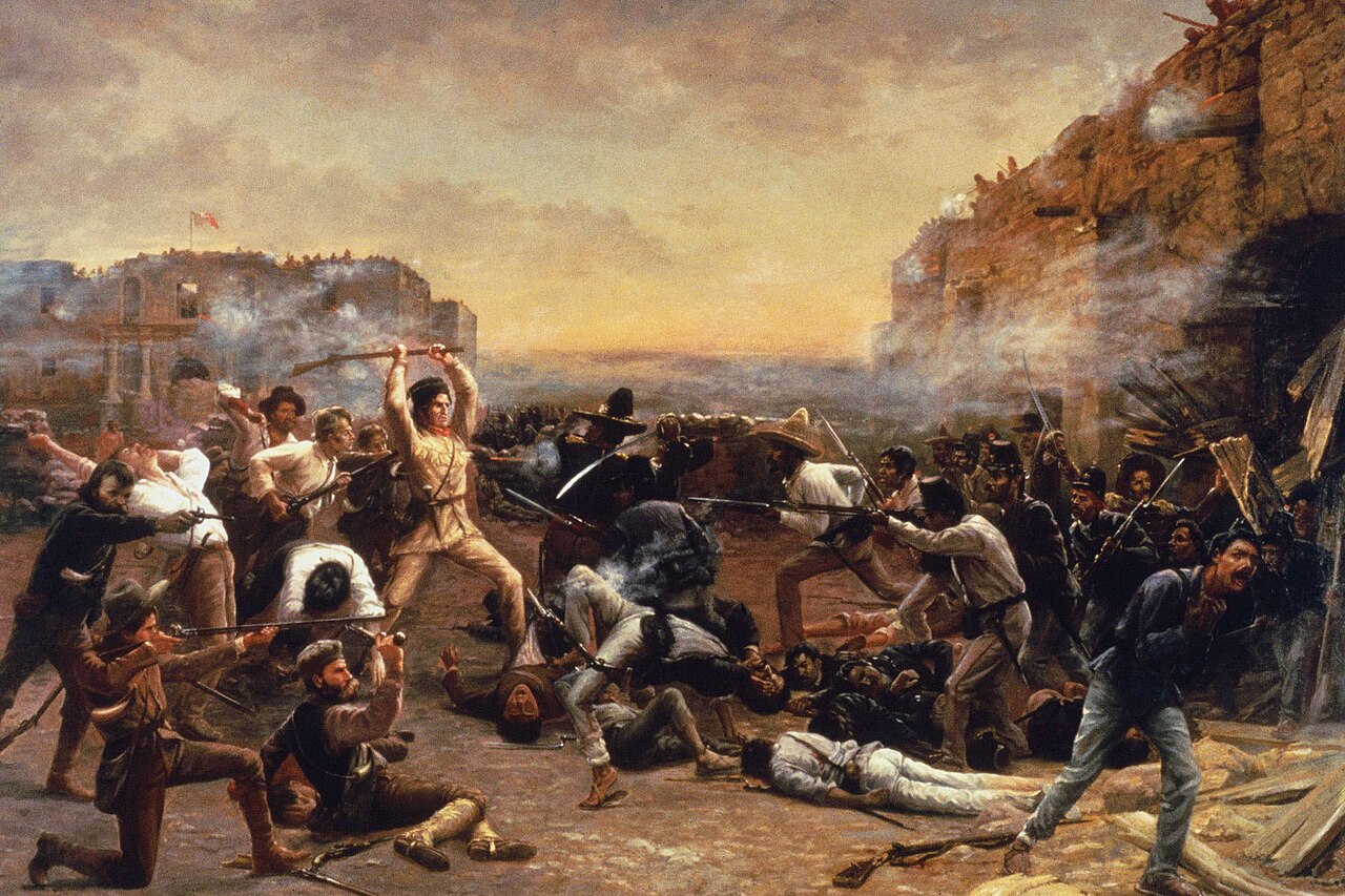 A man in buckskin clothes holds a rifle over his head. He is surrounded by dead soldiers.