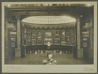 Vue d'ensemble de la rotonde numéro 1 de la Galerie Vasnier avec la verrière comme source de lumière zénithale. Le mur est recouvert de tableaux, devant sont disposés des bustes sur leur socle et des objets d'art à même le sol.