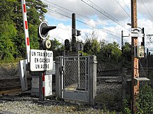 Pohled na bariéru úrovňového přejezdu č. 159 a na přístupovou bránu k trati.