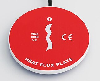 Typical heat flux plate, HFP01. This sensor is typically used in the measurement of the thermal resistance of and heat flux on building envelopes (walls, roofs). Also, this sensor type can be dug in to measure soil heat flux. Diameter 80 mm Hukseflux Heat Flux Plate HFP01.jpg