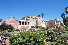 A stone building stands behind a colorful flower garden