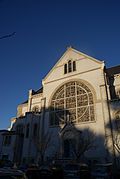 Kleurweergave van de geveltop van een kerk tegen een intens blauwe lucht.