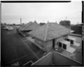 Oblique view from lift-bed truck, showing deteriorated slate roof and chimney,