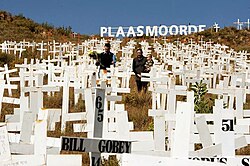 Relatives plant crosses for victims of farm attacks. Bill Gobey (cross shown) was shot in the face in 1987 and his spouse killed at Hekpoort when robbers tried to steal a safe from their rondavel. Plaasmoorde.jpg