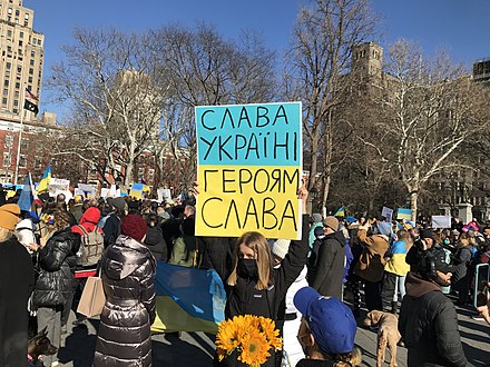 A protester in New York City on 27 February 2022, holding a sign that reads "Glory to Ukraine! Glory to the heroes!" The phrase gained worldwide prominence as a result of the 2022 Russian invasion of Ukraine