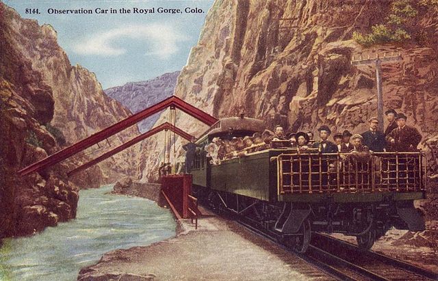Open observation car at the Hanging Bridge of the Royal Gorge on the Denver and Rio Grande Western Railroad in 1918. The enclosed observation car is d