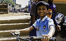 This young boy lives in Dharavi, the worlds third largest slum, in Mumbai, India. Despite his fate of being born into the slum, he still goes to school and is just like any other boys his age. In the background you see the small school yard.