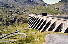 The upper reservoir (Llyn Stwlan) and dam of the Ffestiniog Pumped Storage Scheme in North Wales. The lower power station has four water turbines which generate 360 MW of electricity within 60 seconds of the need arising. Stwlan.dam.jpg